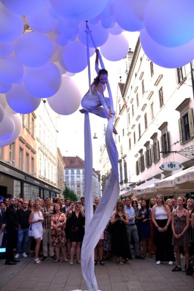 Die Eröffnung des AIOLA Living Stores wurde mit einer Luftakrobatin, die unter weißen Luftballons hoch über der Grazer Schmiedgasse tanzte, gefeiert. (Foto Yasaman Eskandari)